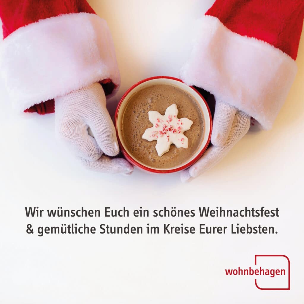 Weihnachten 2022|Hände im Weihnachtsmantel und Handschuhen halten eine Tasse Kakao fest.