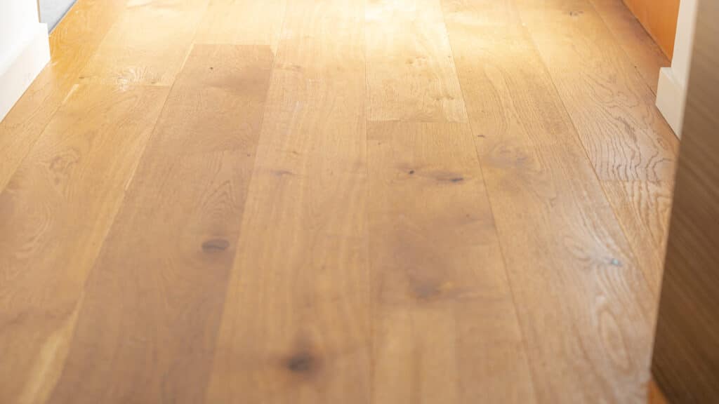 Natürlicher, heller Holzboden mit charaktervollen Maserungen und Aststellen - von Sonnenlicht durchflutet. Die warme Ausstrahlung des Holzes verleiht jedem Raum eine behagliche Atmosphäre und unterstreicht nachhaltiges, modernes Wohnen.